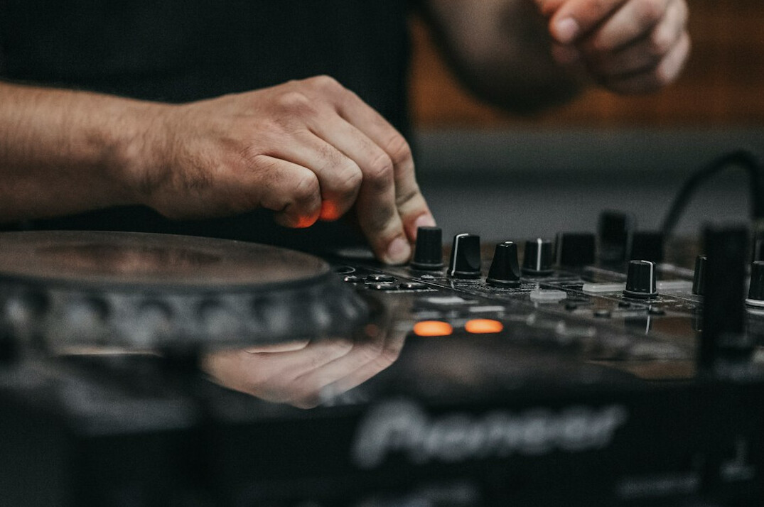 Hand adjusting faders on a professional audio mixing console