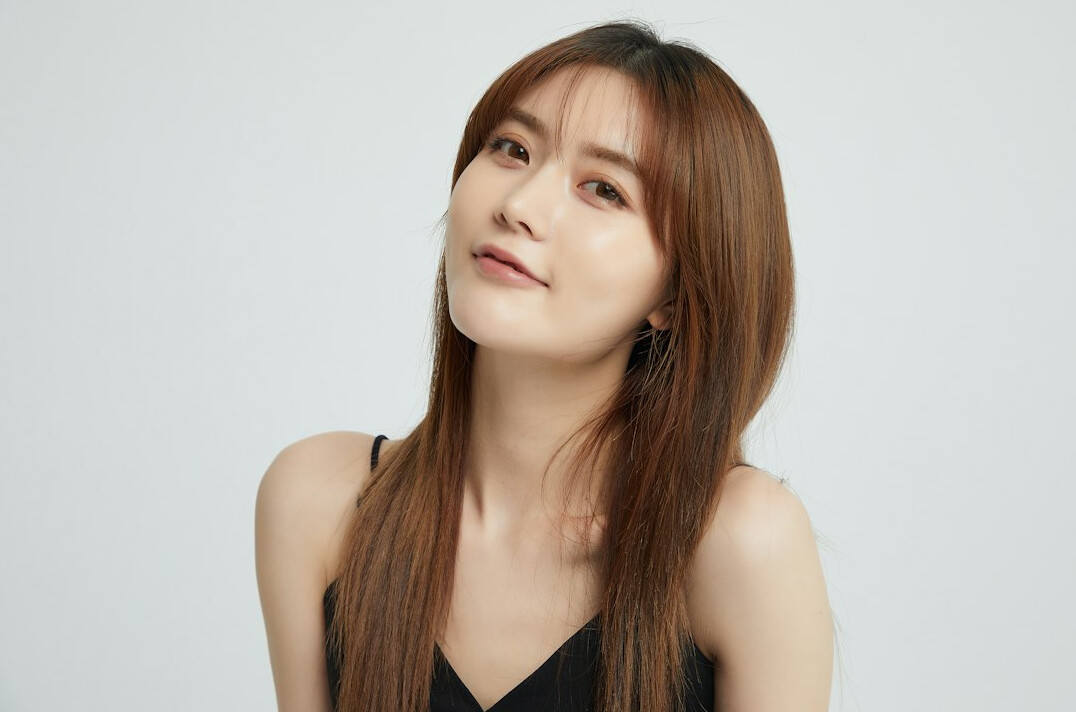 Portrait of a smiling woman with long brown hair in a studio