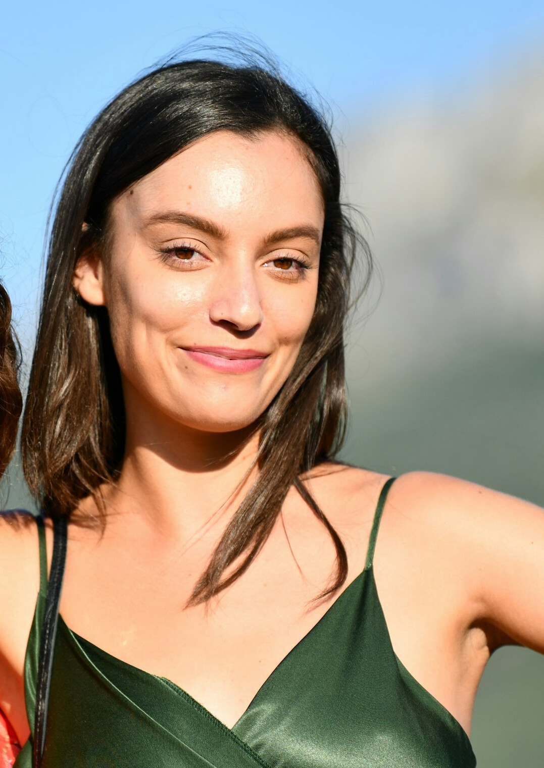 Portrait of a smiling woman with dark hair wearing a green top